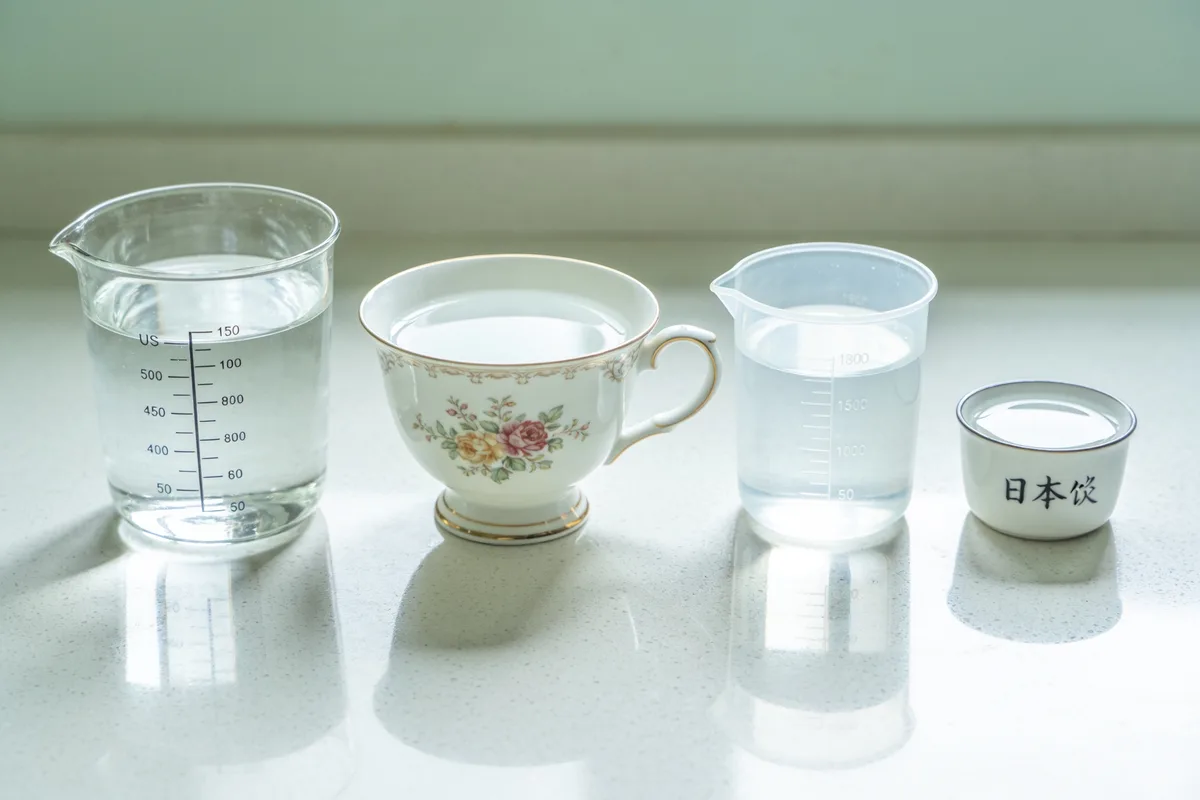 Different cup standards side by side: US, UK imperial, metric, and Japanese rice cups each holding a different volume of water